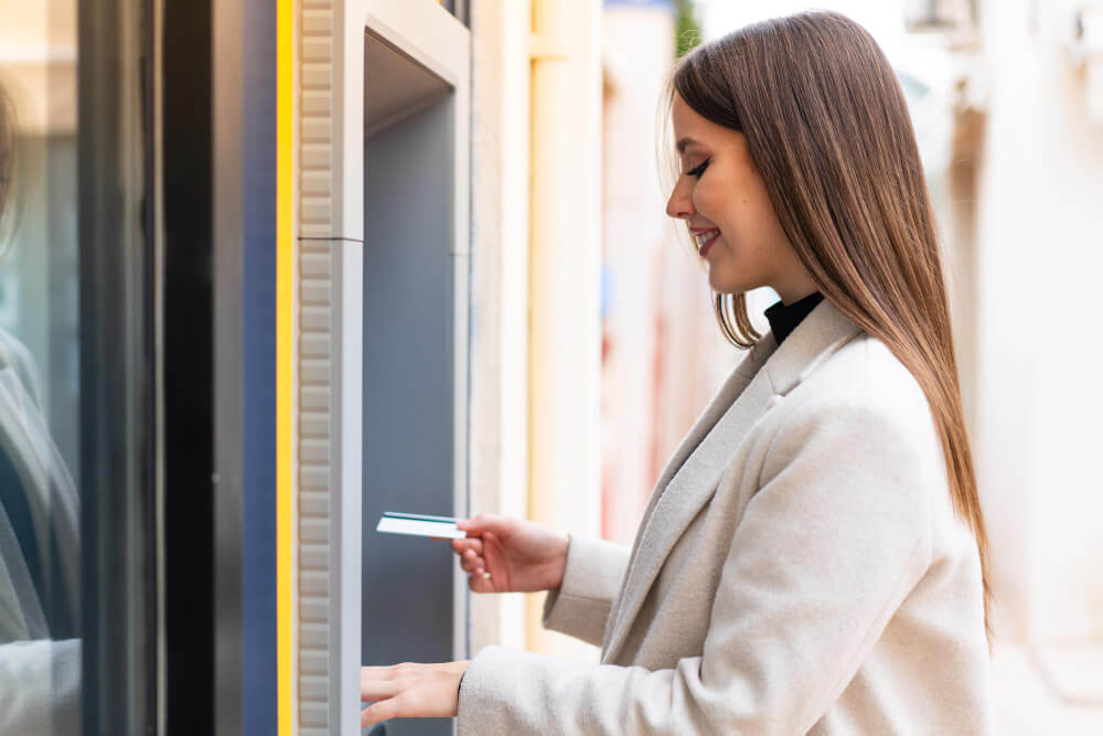 A woman withdrawing money from an ATM outside